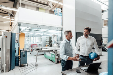 Male engineers discussing over laptop in manufacturing industry