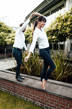 Carefree Colleagues Dancing On Retaining Wall Outside Industry