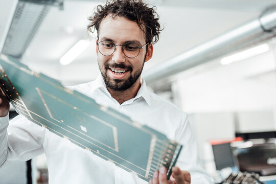 Smiling male engineer examining large computer chip in industry