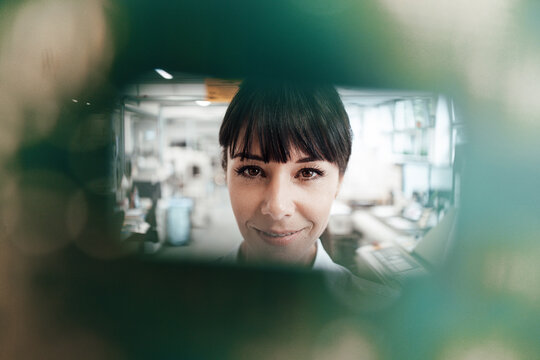 Smiling female engineer looking through computer chip in manufacturing industry