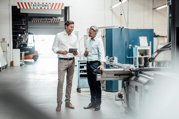 Happy mature businessmen discussing while standing in factory