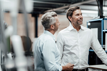 Male colleague discussing with smiling manager in manufacturing industry