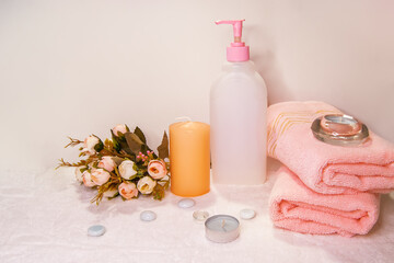 Obraz na płótnie Canvas Spa still life - a flowers, shower accessories and towels on a white background. Beige, pink and white tones.
