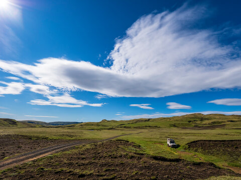 Clouds over remote Icelandic dirt road on sunny day