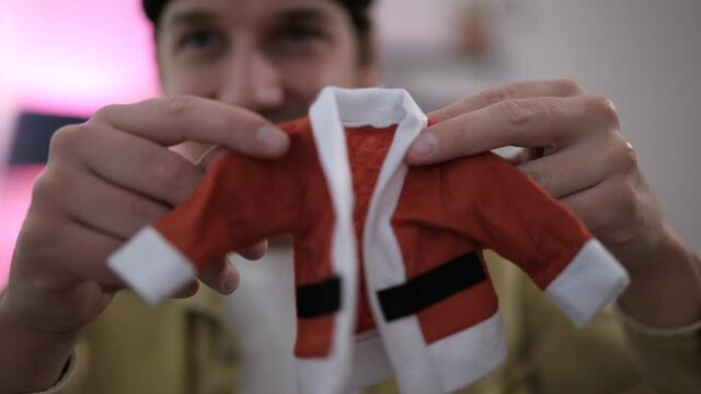 Young man playing with super tiny Christmas baby suit