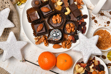 sweet food top view background for merry christmas or new year holiday decoration - chocolate candies, tangerines, cookies on white wood