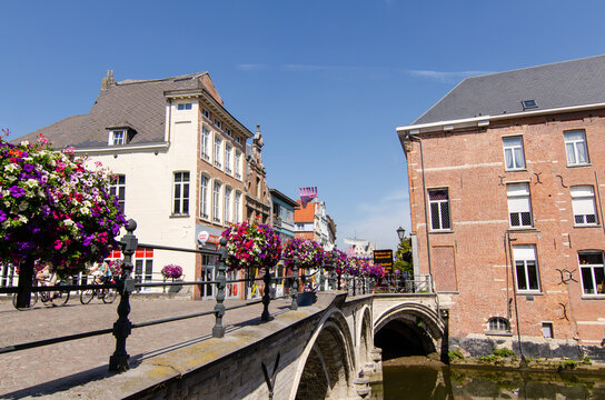 Mechelen, Belgium, August 2019. In the historic center, the bridges are decorated with brightly colored flower boxes. People walk along the sidewalk, beautiful sunny summer day.