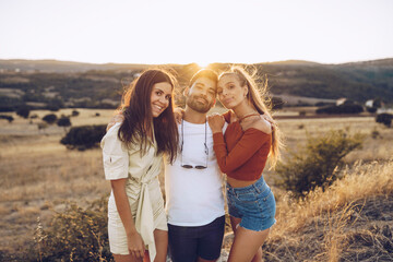 Smiling young man with female friends standing on field