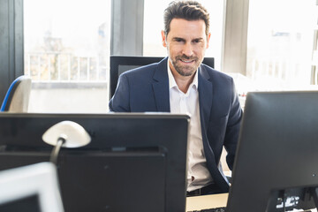 Businessman wearing suit working on computer while sitting at office