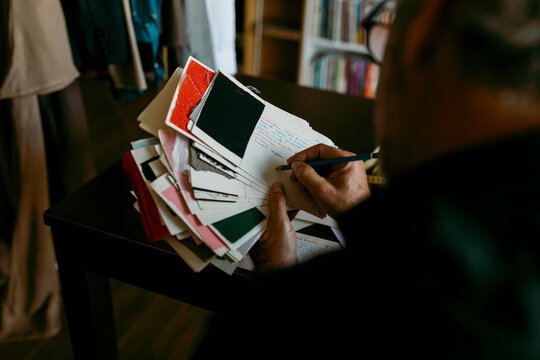 Male tailor writing on paper with pencil while working in studio