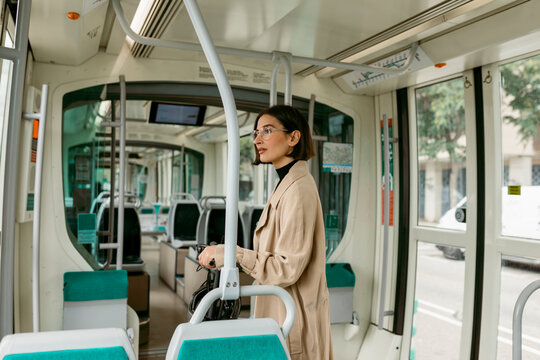 Woman looking away while standing with push scooter in tram