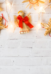 Christmas festive background from straw festive decorations and a Christmas angel with a red bow on a light background. Upper layout. Copy space.