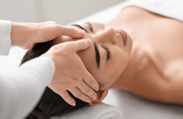 Obraz na płótnie Canvas Spa therapist making relaxing head massage for beautiful asian woman in salon