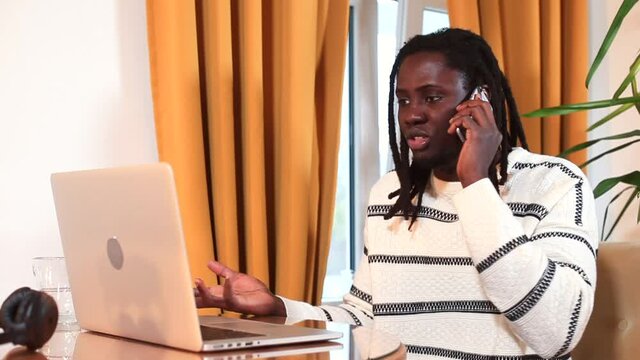 Afro man calls support by phone, reports a breakdown of the Internet in a laptop. Randomly presses the keys with his hand, speaks emotionally. Communication using the telephone network.