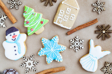 Fototapeta na wymiar Gingerbread painted colored gingerbread cookies and spices and snowflakes on a craft background close-up. Christmas celebration concept. New Year's food