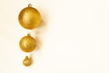 Fototapeta premium Three golden Christmas balls of different sizes are displayed in a row as a border on a white background. Copy space.