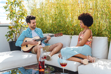 Smiling man in love playing guitar for black woman