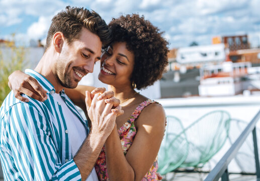 Pretty interracial couple on roof holding hands and laughing