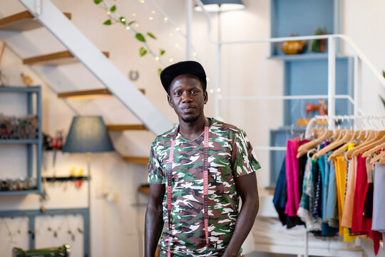 Confident young male trainee with tape measure standing at design studio