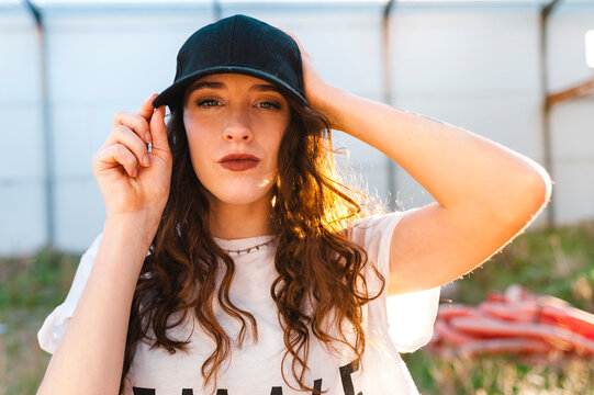 Young woman hip-hop dancer posing with a baseball cap in an abandoned building