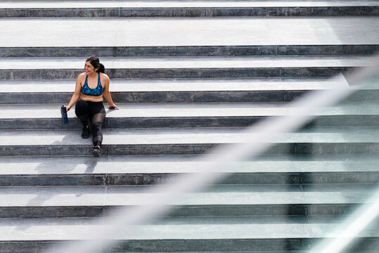 Young athletic woman sitting on stairs during break