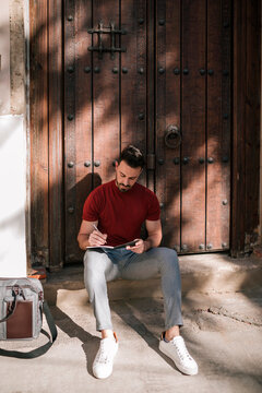 Businessman writing in book while sitting at doorstep