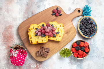 top view raisin cake slices on cutting board bowls with raisin and raspberry candies and xmas toys on marble ground