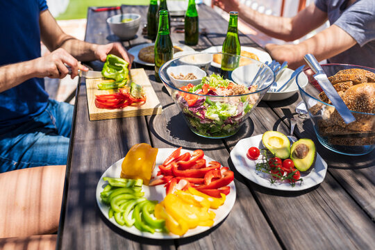Close-up of brunch on table with young friends sitting at building terrace