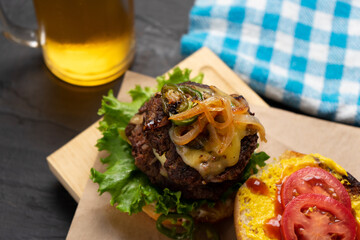 Cheese burger with caramelized onion and jalapeno pepper on dark background