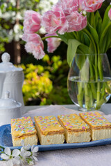 Tompouce cakes with whipped cream and yellow icing served in sunny spring garden