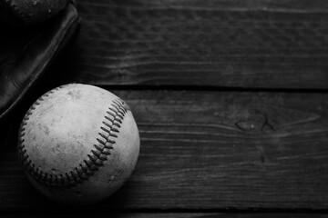 Old baseball with glove on wood texture in black and white.