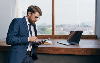 A man in a suit with a tablet in the hands of an office laptop technology Professional