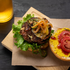 Cheese burger with caramelized onion and jalapeno pepper on dark background