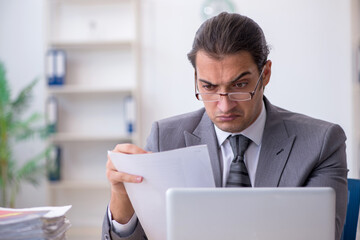 Young male employee reading contract paper in the office