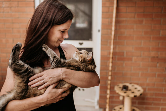 Close-up of mature woman carrying cat while standing against house