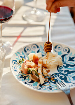 Hand Holding Honey Dipper Above Plate