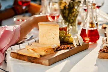 Cheese platter and wine on table with people in background