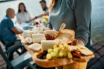 Friends having dinner with a cheese platter at a lake