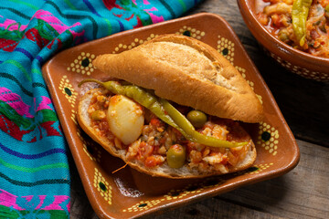 Mexican style cod sandwich called torta a la vizcaina on wooden background