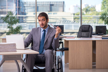 Young male employee in wheel-chair working in the office