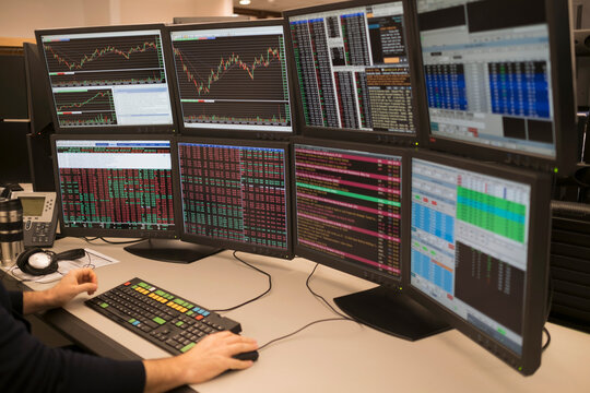 Young man working on group of computer monitors
