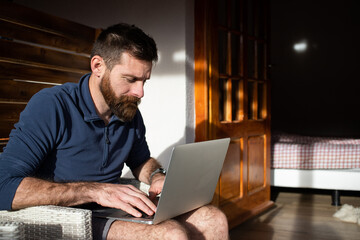 man working on laptop in wooden cottage