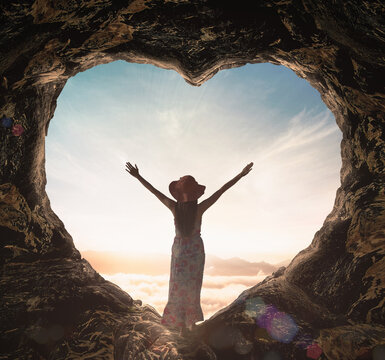 Worship God concept: Silhouette alone woman standing on cave of heart and sea of fog sunrise background