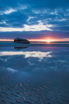 USA, Massachusetts, Cape Cod, Orleans, Rock reflecting in sea at sunset