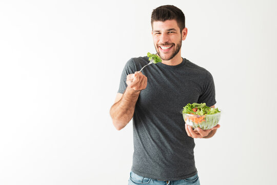 Healthy young latin man holding his green salad and fork