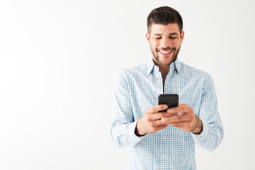 Hispanic man is happy and sending a text on his smartphone