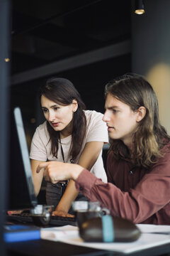 IT professional with male colleague working on laptop in office