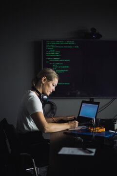 Side view of IT professional working on laptop in creative office