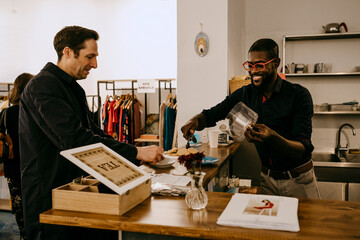 Smiling owner serving baked pastry item to customer in cafe