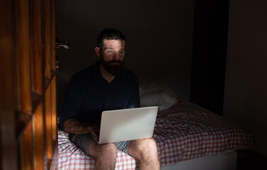 man working on laptop in wooden cottage